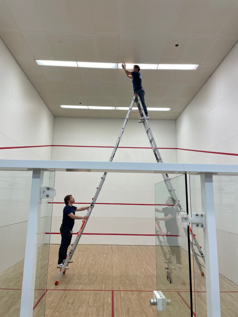 rec tech students working on a ladder in raquetball court