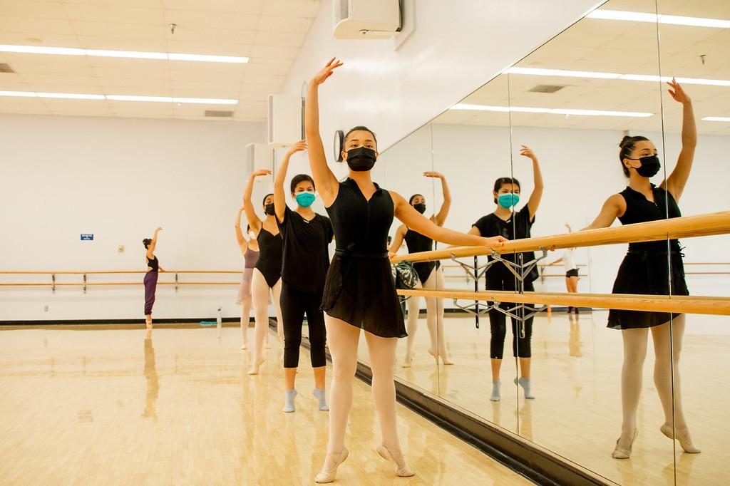 Group of students practicing ballet with a bar