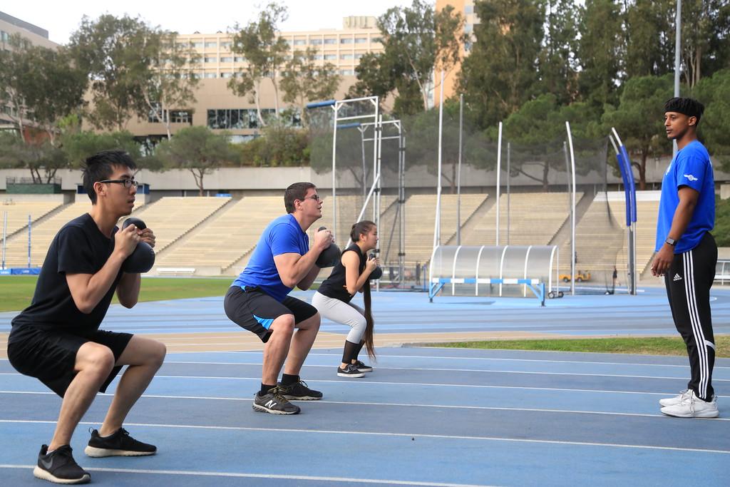 Group of three students squatting with a kettlebell 