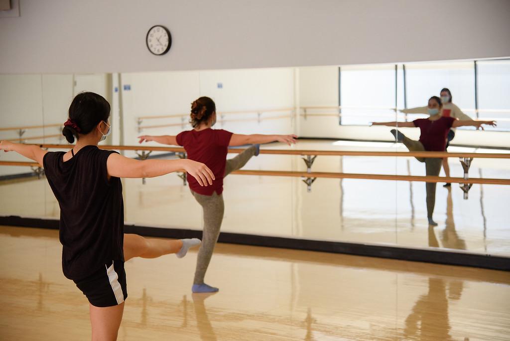 Group of students dancing in front of a mirror with one foot in the air 