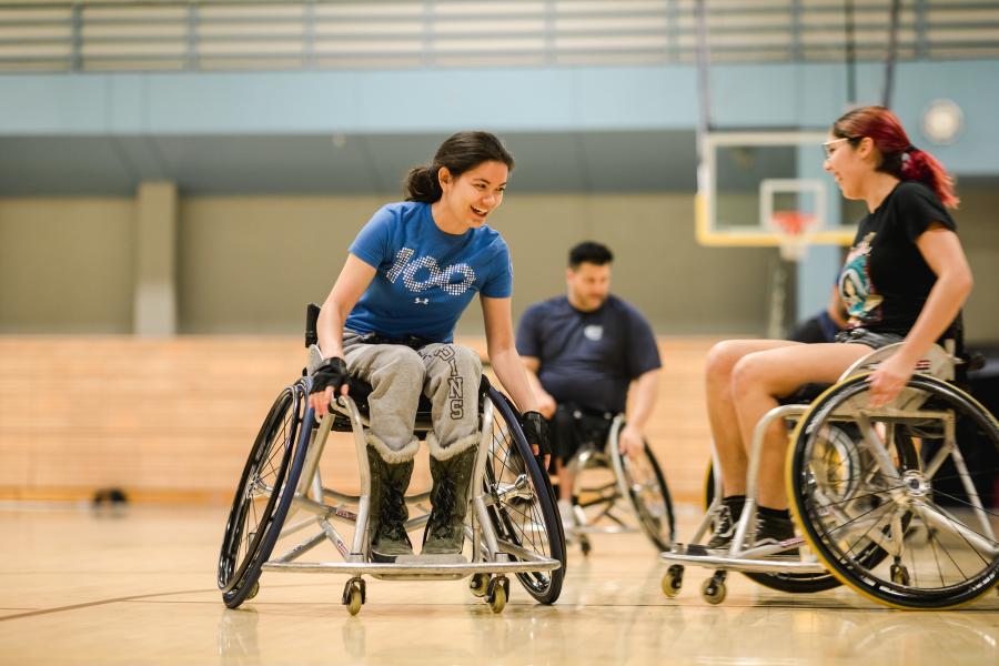 Two females playing basketball in wheelchairs