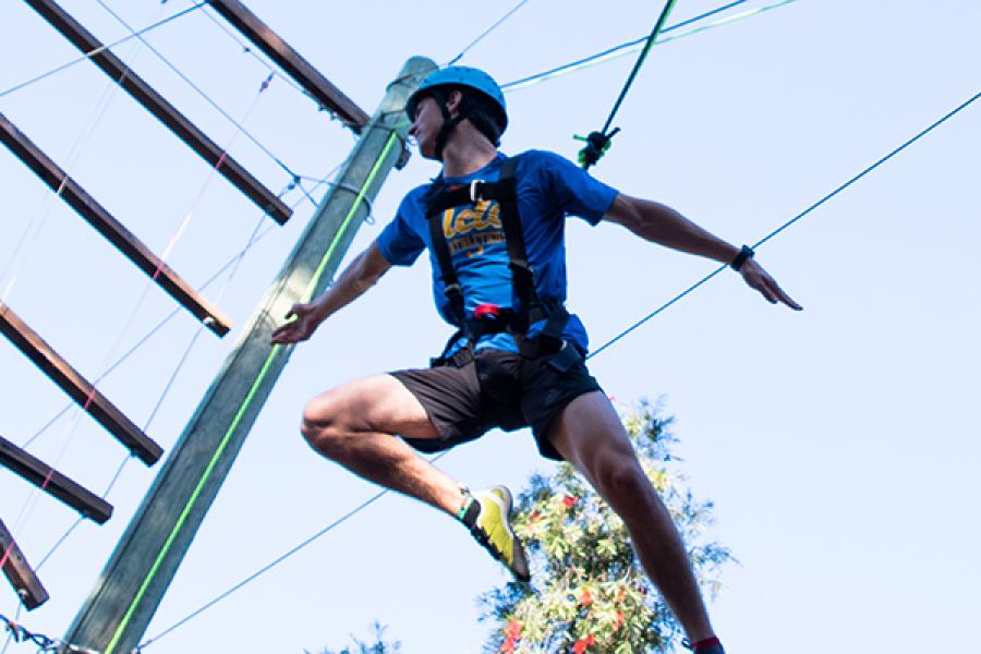 Challenge Course participant hanging from ropes