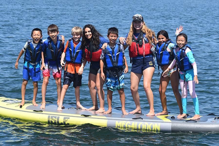 group of kids posing on stand up paddleboard