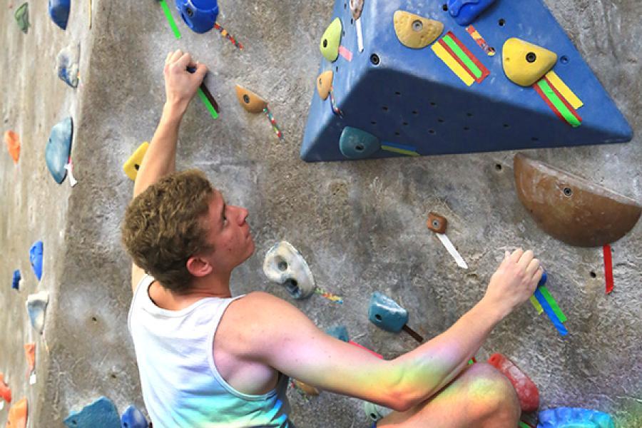 A male student climbing the rock wall 