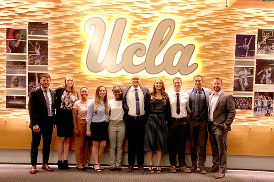 A group of students and staff standing by the UCLA sign 