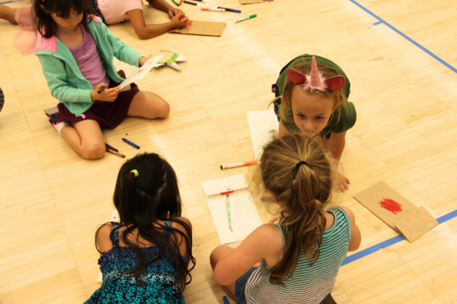 Group of young kids in sitting on the ground coloring