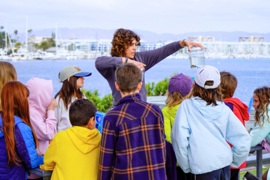 group of kids listening to camp counselor overlooking the marina