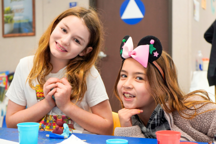 two young girls smiling for the camera while crafting
