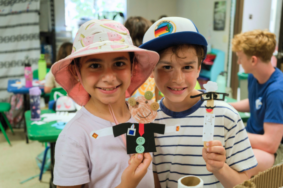 two kids smiling for a photo showing their craft
