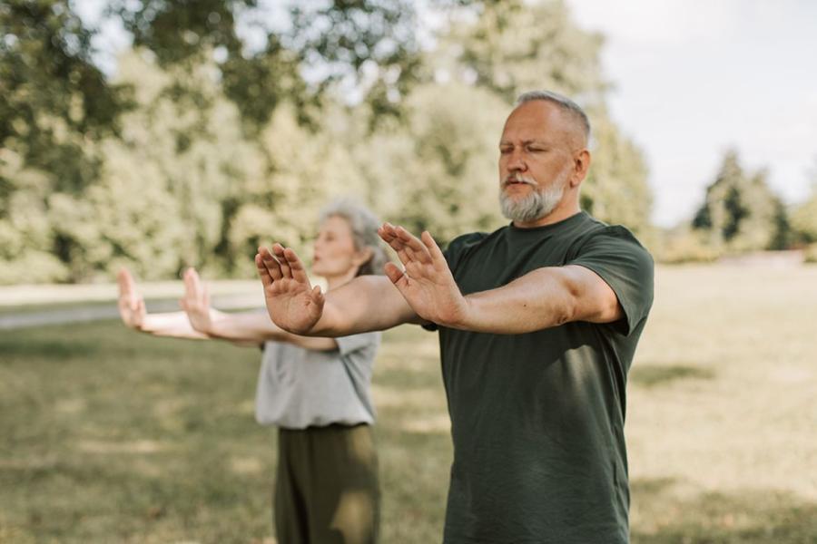 Older man and woman in park doing QiGong exercises