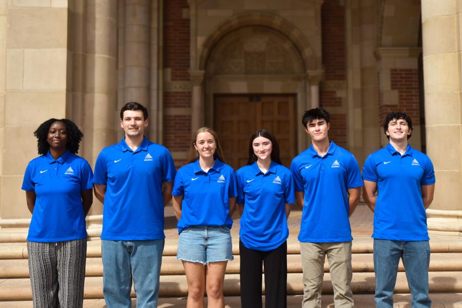Staff in blue shirts lined up in front of stairs
