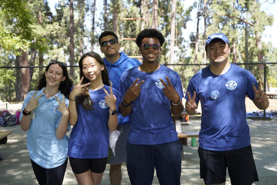 summer camp staff in blue shirts with trees in background